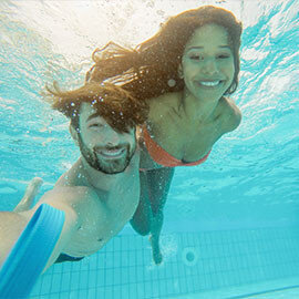 Couple swimming underwater in a pool