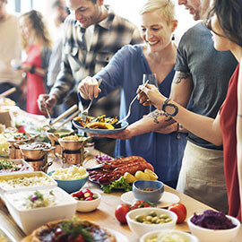 A group of people serving themselves food at a catered party