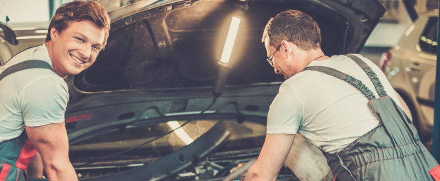 Two mechanics working under the hood of a car