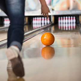 A bowling ball being rolled down a bowling alley