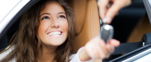 A woman in a car receiving a set of keys