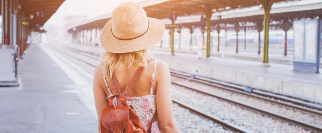 A woman with a backpack waiting at a train station