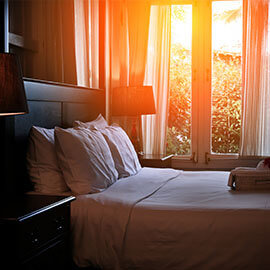 Sun shining in though a window on a made bed at a hotel