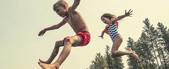 Two children jumping into a lake