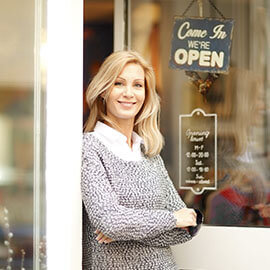 A business owner at the front door of her open establishment