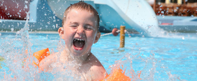 A boy splashing around in a pool