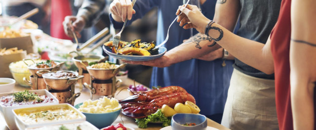 A group of people serving themselves food at a catered party